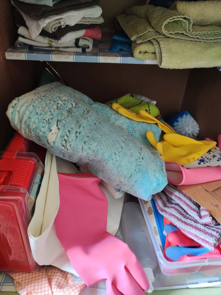 This is a cabinet that is visually cluttered with disorganized cleaning supplies.